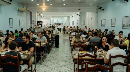 Clientes descontraídos no salão acolhedor e familiar do Rainha Restaurante